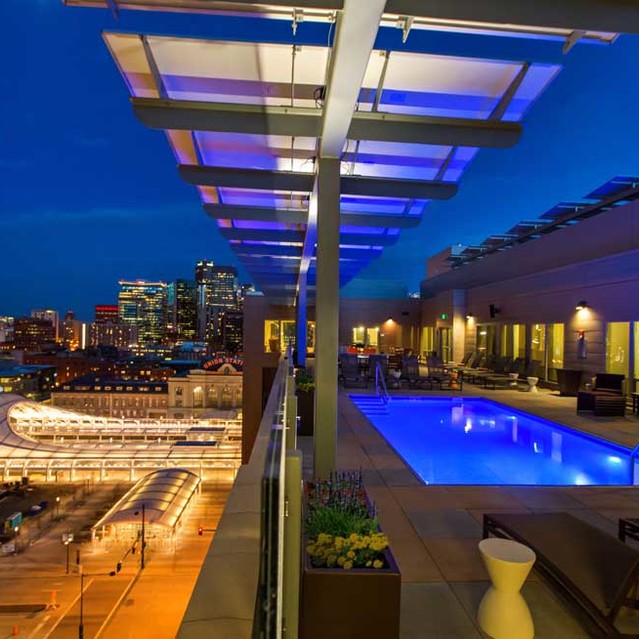 Cadence Union Station Apartments - Rooftop Pool with Lounge Chairs and City Skyline View at Night 