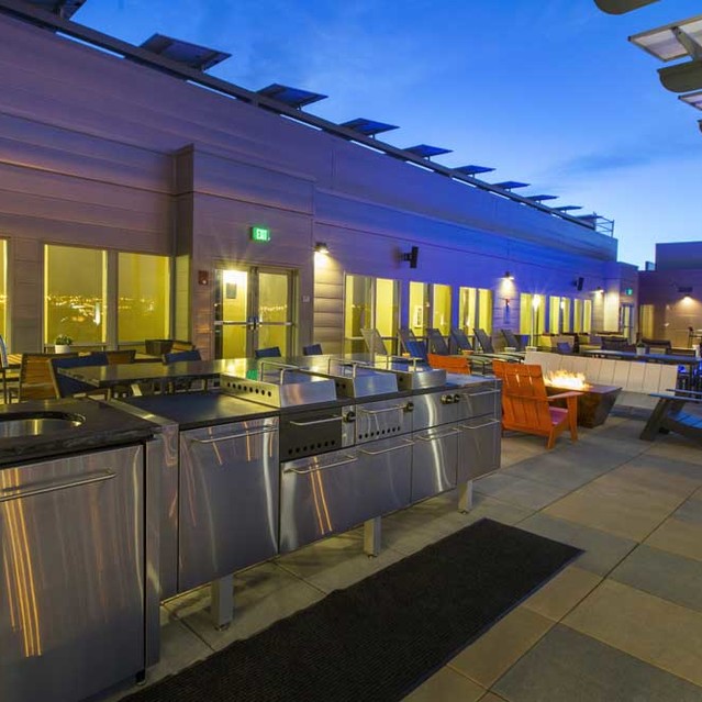 Cadence Union Station Apartments - Rooftop Patio with Stainless Steel Grills, Outdoor Seating, and Modern Lighting at Dusk 