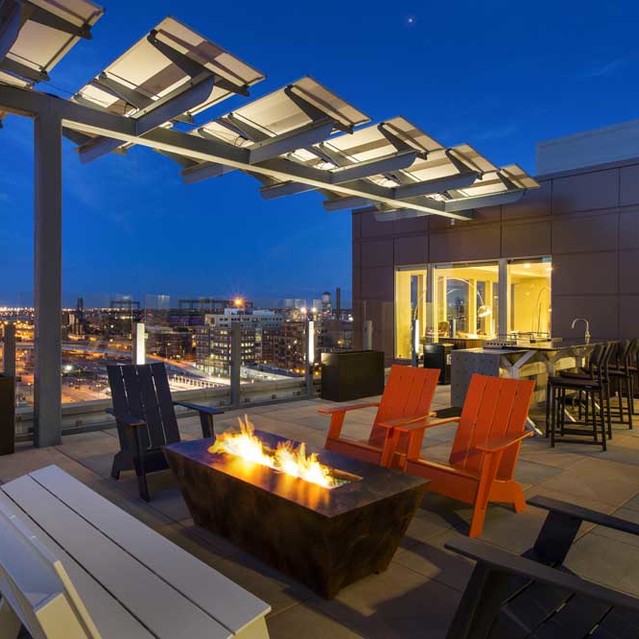Cadence Union Station Apartments - Rooftop Patio at Dusk with Fire Pit, Modern Furniture, and City Skyline View