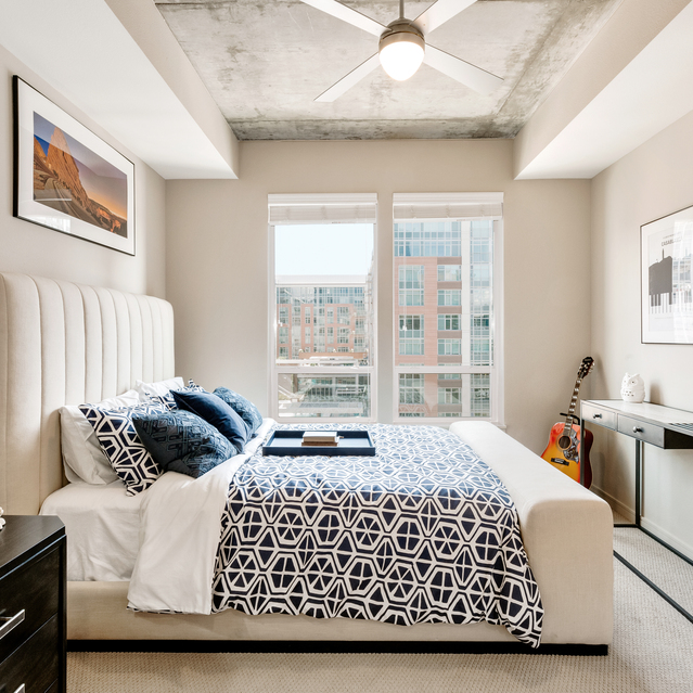 Cadence Union Station Apartments - Modern Bedroom with Large Bed, Blue and White Bedding, Windows, and Ceiling Fan