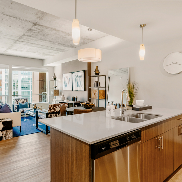Cadence Union Station Apartments - Modern Open-Concept Kitchen and Living Room with Wooden Floors, Large Island, Pendant Lights, and Cozy Seating Near Big Windows 