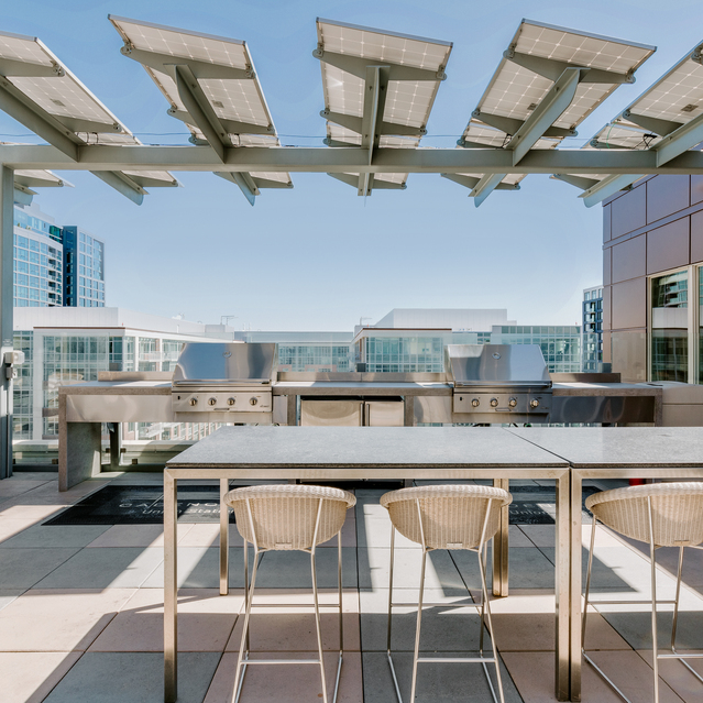Cadence Union Station Apartments - Rooftop Patio with Tables, Chairs, Pergola, and City View Under Clear Blue Sky 